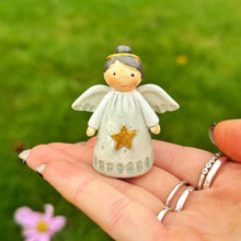 Small angel figurine held in a hand with a blurred green background