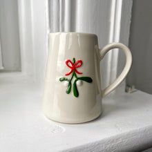 White ceramic mug with a red flower design on a white surface