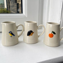 Three ceramic mugs with animal illustrations on a windowsill.