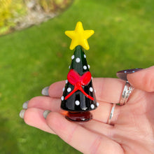 Small decorative Christmas tree with a yellow star on a hand against a green grass background