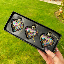 Heart-shaped decorative ornaments in a box held by a hand outdoors.