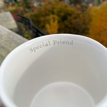 White cup with 'Special Friend' text against a blurred autumn landscape