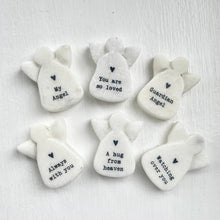 Set of white stone angel figurines with engraved messages on a light gray background