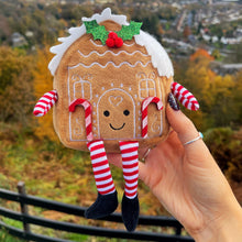 Gingerbread man plush toy held in front of a scenic landscape