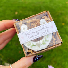 Hand holding a small box with a decorative item against a green grass background