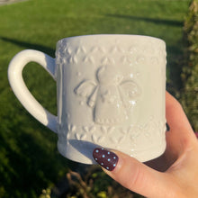 White textured mug held by a hand with a garden background