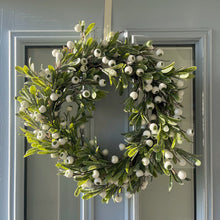 Green wreath with white berries on a gray door