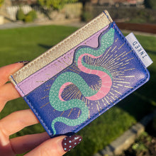Cardholder with snake design held by a hand outdoors