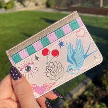 Cardholder with colorful designs held by a hand outdoors