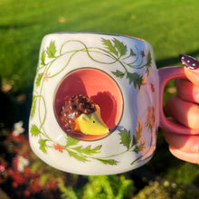 Mug with hedgehog design held outdoors on a sunny day