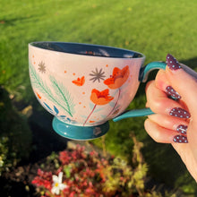 Person holding a colorful mug with floral design outdoors