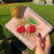 Pink pouch with cherry design held by a hand outdoors