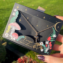 Hand holding a black jewelry box with floral designs outdoors
