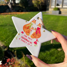 Star-shaped ornament with foxes and text held by a hand outdoors.