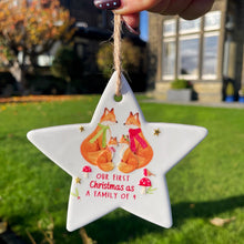 Star-shaped ornament with foxes and text held by a hand outdoors.