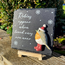 Slate with a robin decoration and text on a wooden surface outdoors