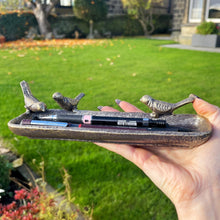 Hand holding a decorative tray with bird designs outdoors