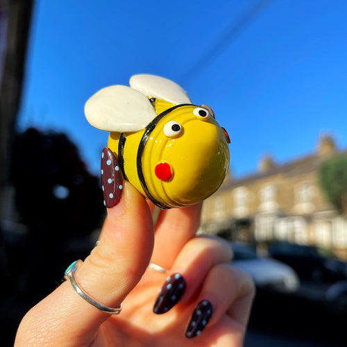 Hand holding a small bee-shaped object against a blurred background