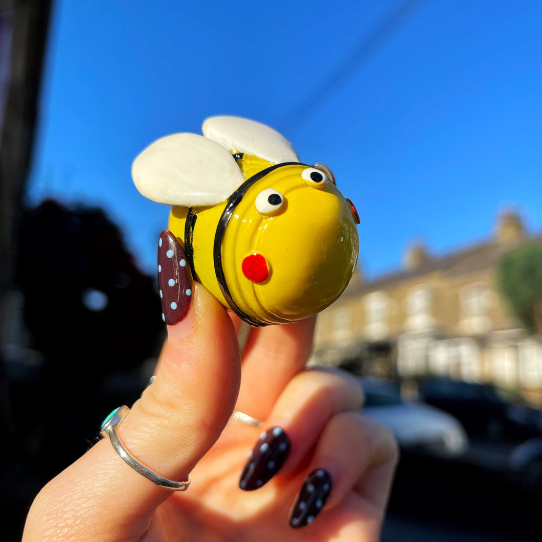 Hand holding a small bee-shaped object against a blurred background