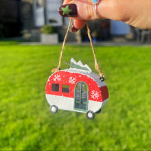 Hand holding a red and white caravan ornament with a star on grass