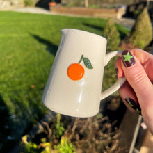 White mug with orange design held outdoors